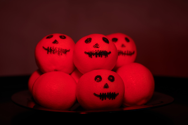 Plate of Tangerines with Painted Halloween Faces by Red Lighting